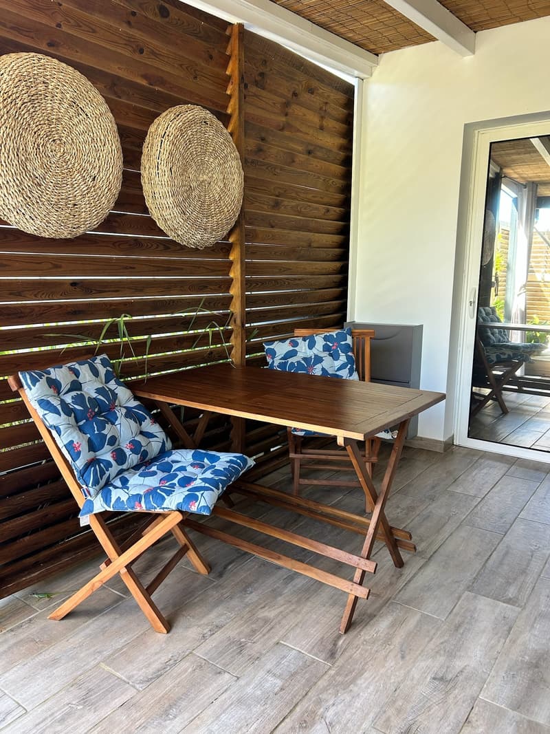 Le coin repas de la terrasse, deux chaises pliantes et une table en bois